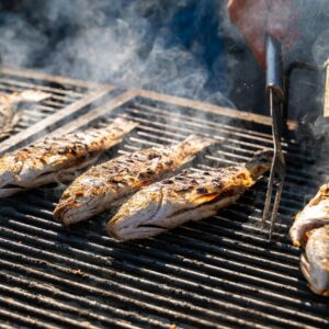 Grilled fish smoking on a barbecue grill, capturing outdoor summer cooking ambiance.